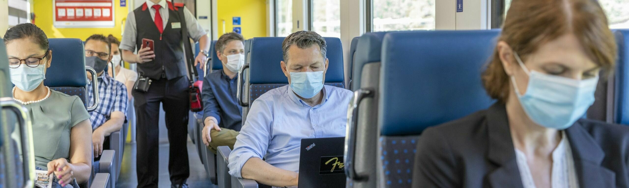 Les clients sont assis dans le train avec des masques.