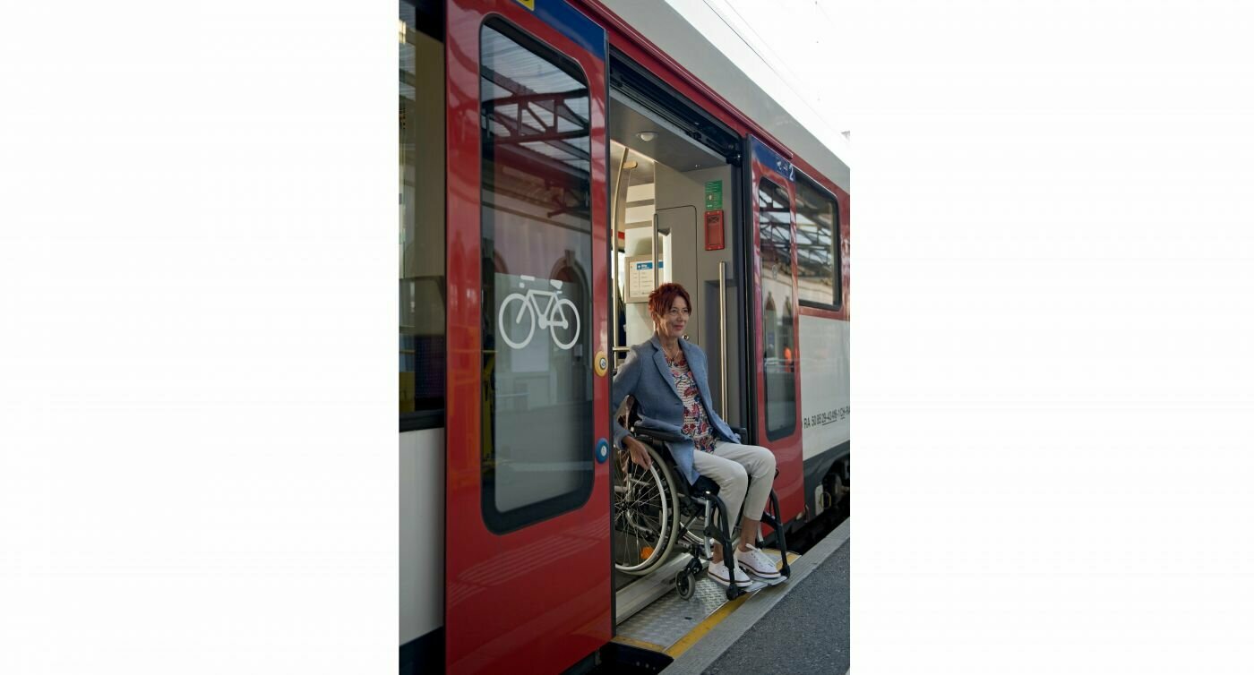 Donna in sedia a rotelle che utilizza l'uscita a livello di un treno