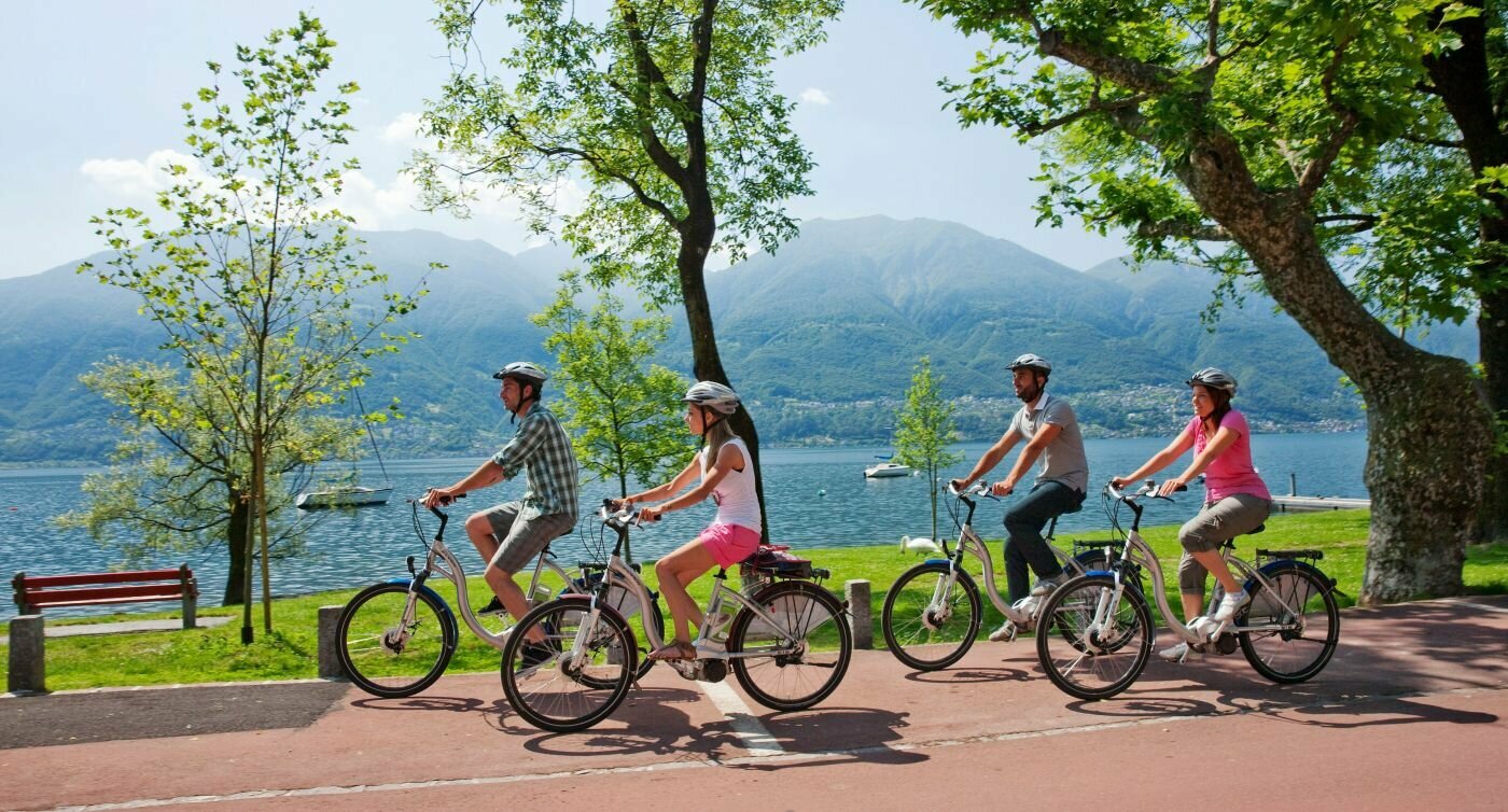 Zwei Paare mittleren Alters fahren auf E-Bikes entlang des Lago Maggiore.