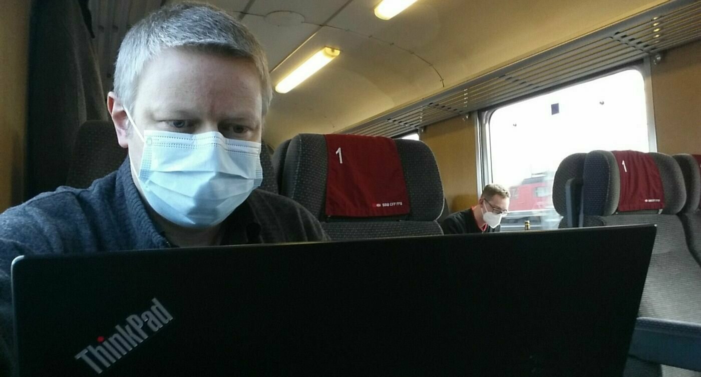 Uomo in treno davanti al computer portatile