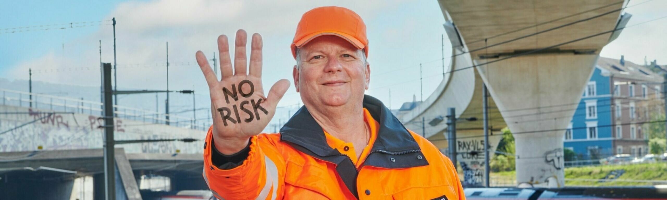 Un homme en tenue de travail tend la main avec l'inscription "No Risk"