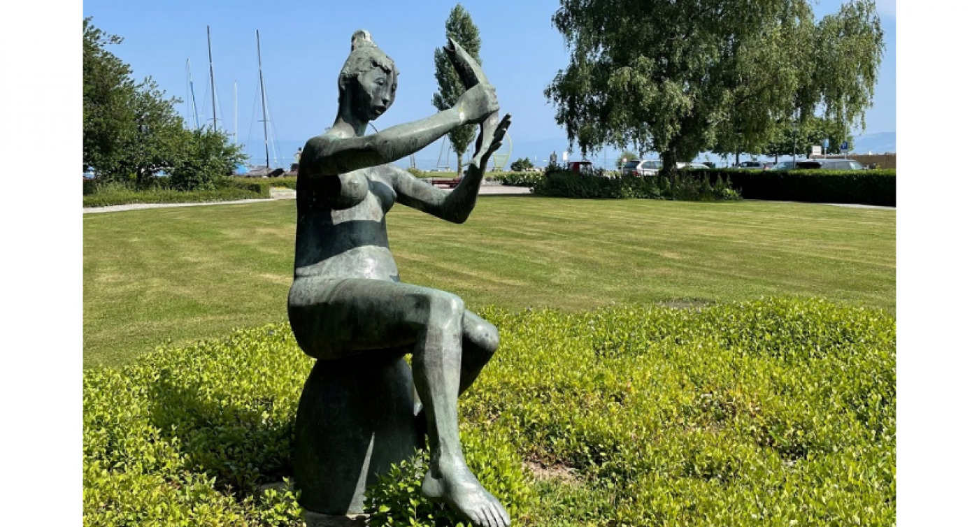 Bronze Skulptur von einer Frau mit Fisch in der Hand auf einem Rasen