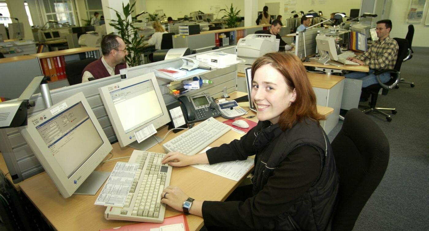 Bureau paysager, femme assise à une table de bureau devant un ordinateur