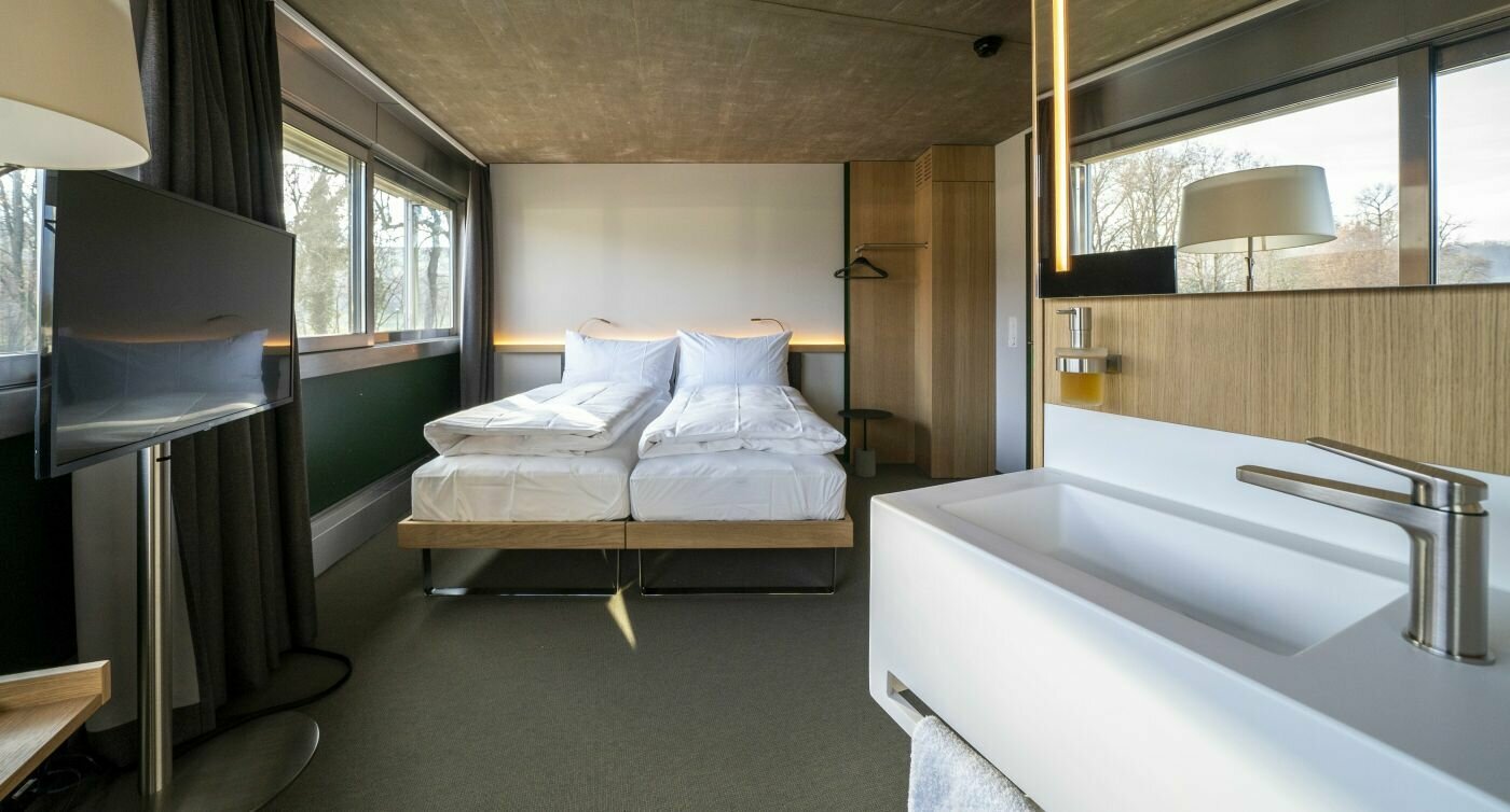 chambre double moderne avec lits, télévision et lavabo