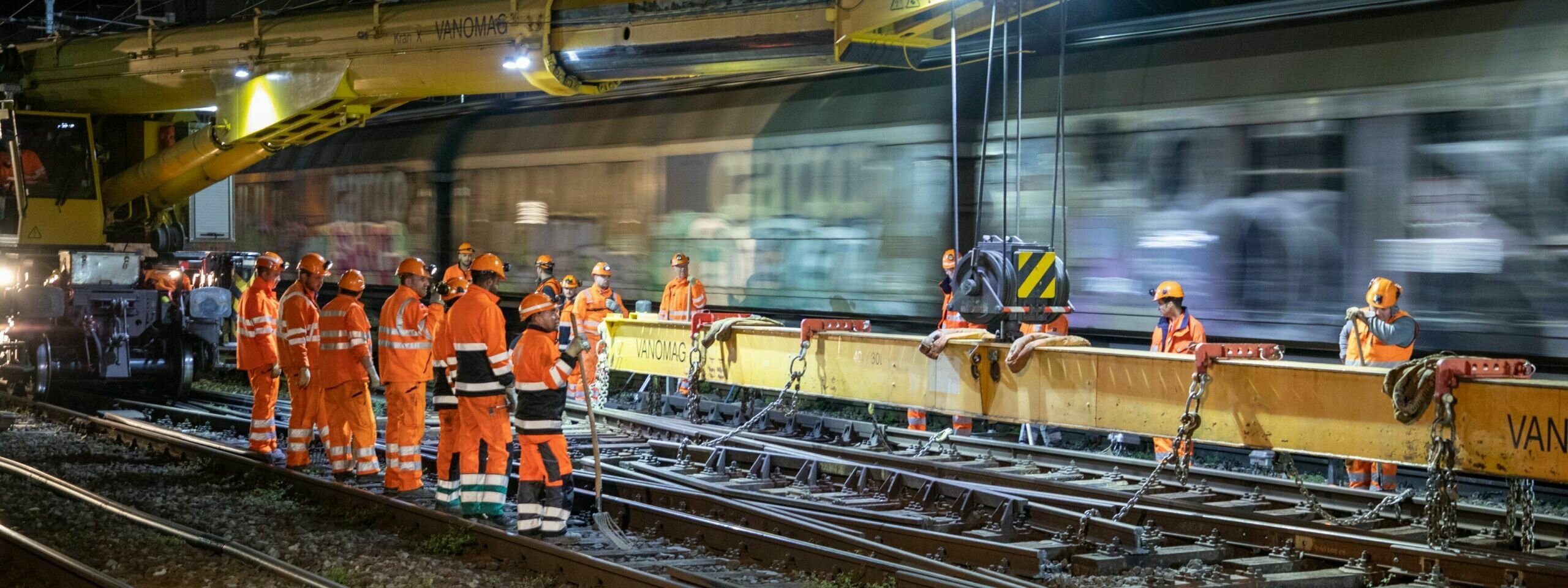 Das Bild zeigt Mitarbeitende, die Schienen abladen.