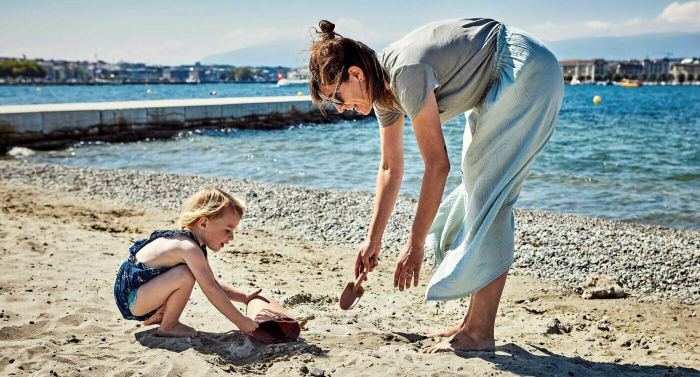 Emilie gioca con la figlia sulla sabbia.
