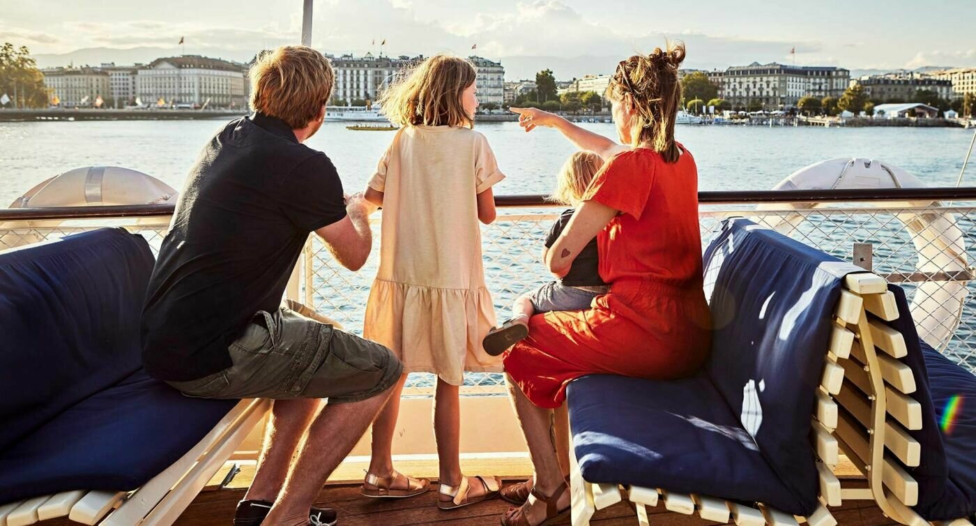 Depuis le bateau, la famille Servettaz contemple la ville de Genève baignée dans la chaude lumière du couchant.