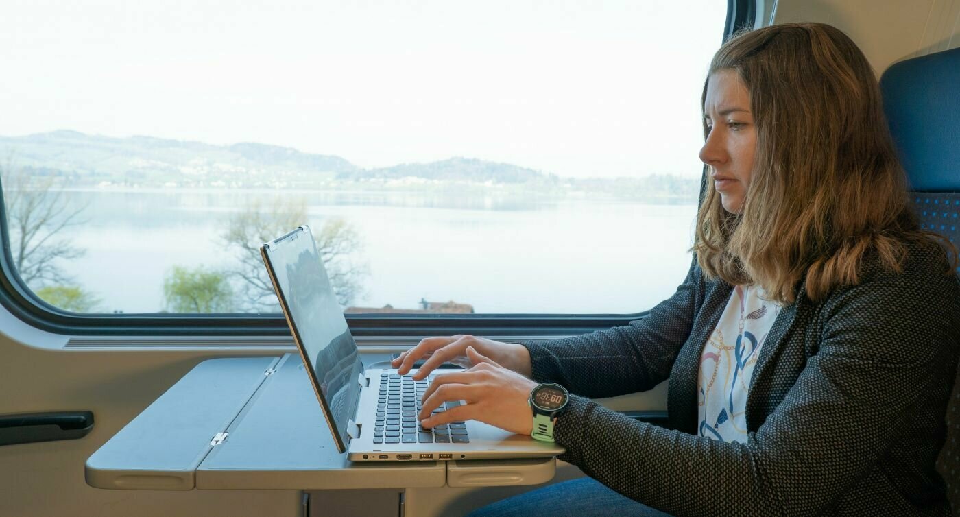 Vanessa Hänni siede nello scompartimento del treno e lavora al computer portatile