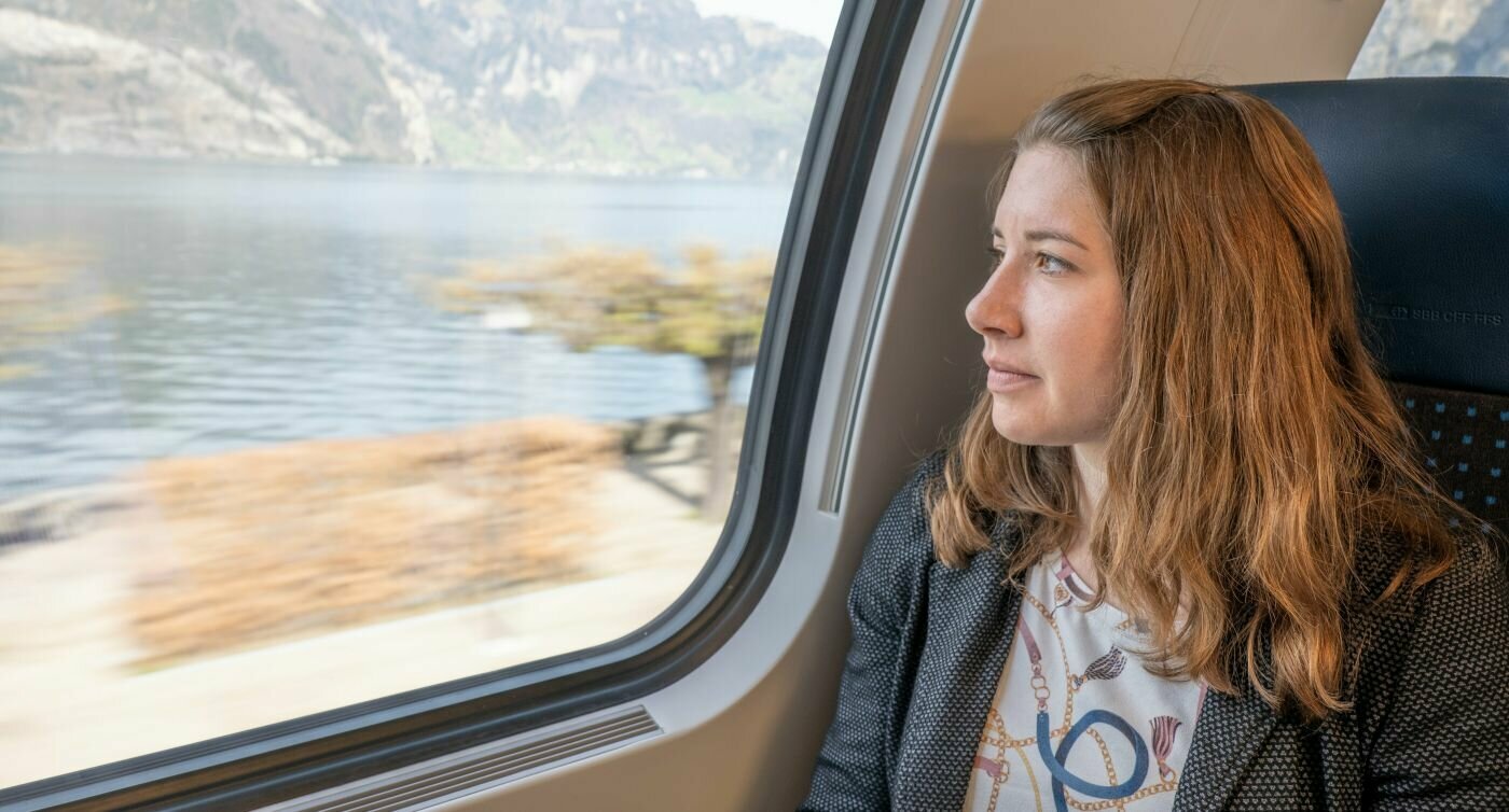 Vanessa Hänni guarda fuori dal finestrino del treno. Sullo sfondo si vede un lago.