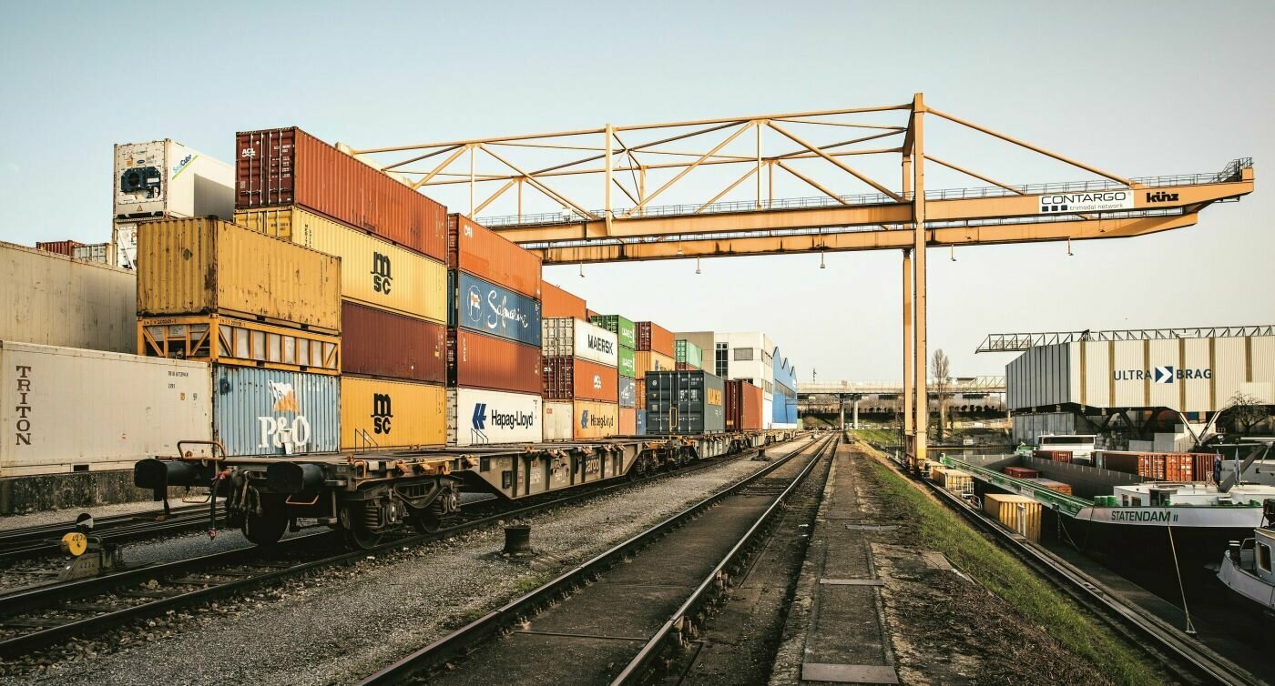Güterzüge mit Containern neben Hafenanlegestelle