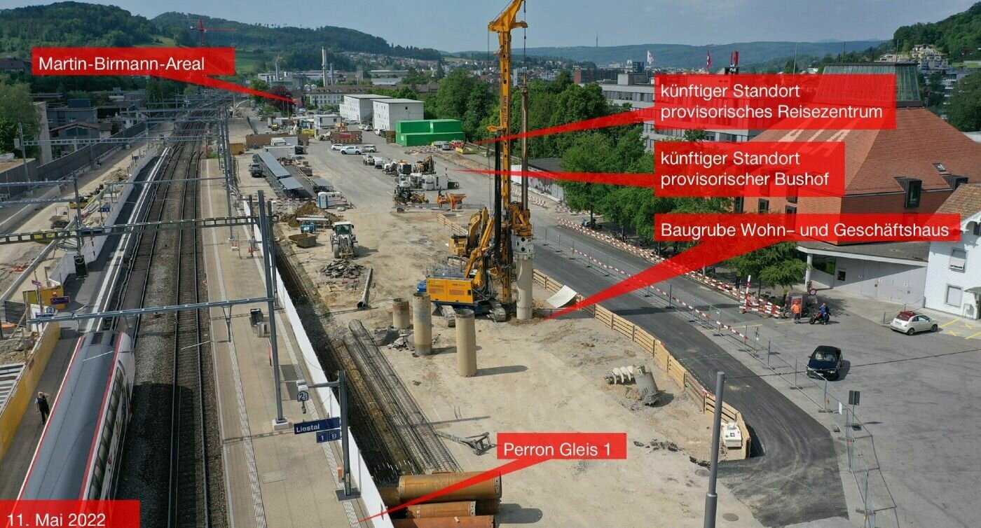 Baustellenansicht vom 11. Mai 2022 mit Beschriftungen: Das Martin-Birmann-Areal im Hintergrund, den künftigen Standorten des provisorischen Reisezentrums und Bushaus, der Baugrube Wohn- und Geschäftshaus und dem Perron Gleis 1.
