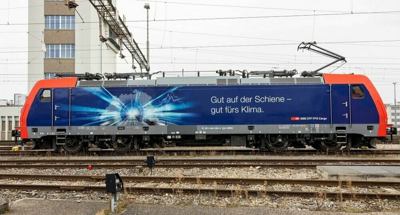 Vista laterale di un treno merci con la scritta "Buono su rotaia - Buono per il clima" in tedesco.