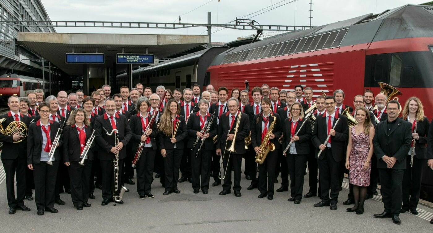 Die SBB Live Band ist vor einem Zug welcher im Bahnhof Luzern steht aufgereiht
