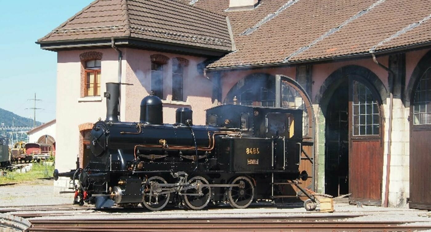 Une locomotive à vapeur se trouve devant le dépôt de Delémont
