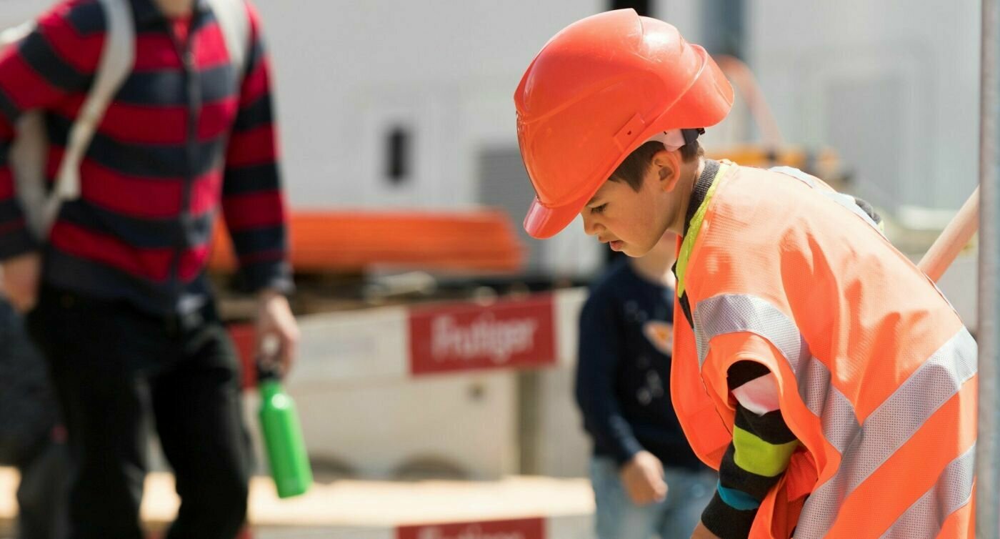 Un garçon est déguisé en ouvrier du bâtiment et joue avec des outils sur le chantier.