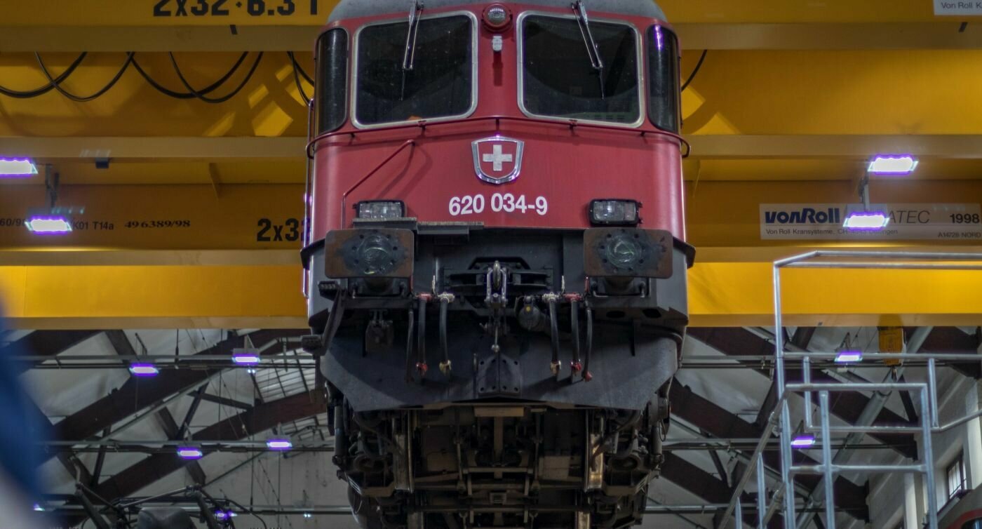 Lokomotive Re 620 hängt an einem Kran von der Decke.  
