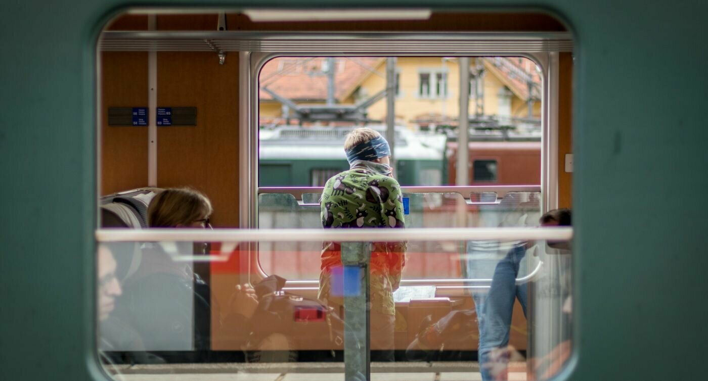 Un ragazzo guarda fuori dal finestrino aperto del treno. 