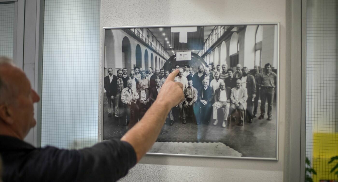 Kari zeigt mit dem Finger auf sich auf dem Gruppenfoto von allen Mitarbeitenden des Kraftwerkes.