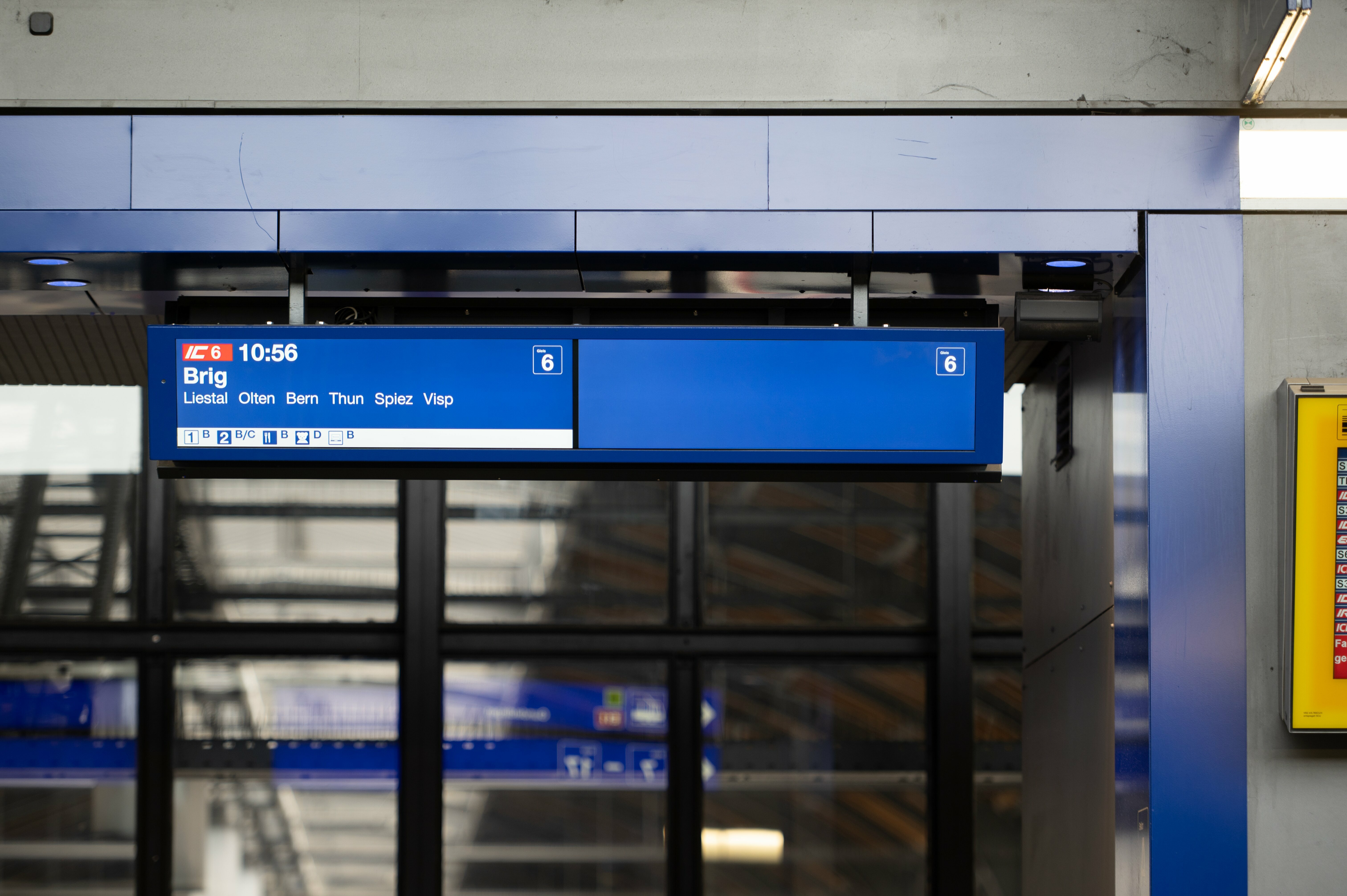 Ein Zugangsanzeiger mit hellgrauem Informationsbalken am Bahnhof Basel SBB mit Beispiel IC6 nach Brig.