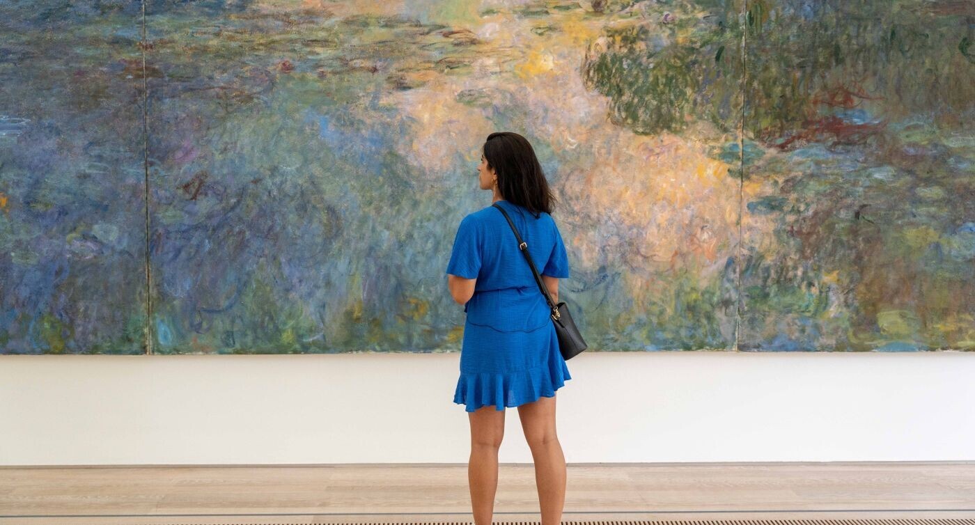 Eine Frau steht vor einem grossen, abstrakten Gemälde.