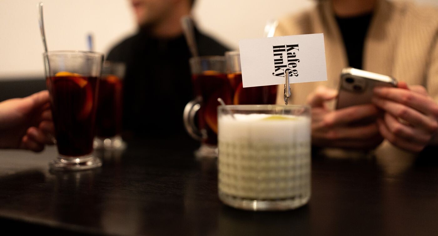 Un cappuccino sul tavolo e un biglietto con la scritta Kafe & Hrnky al centro dell'attenzione.