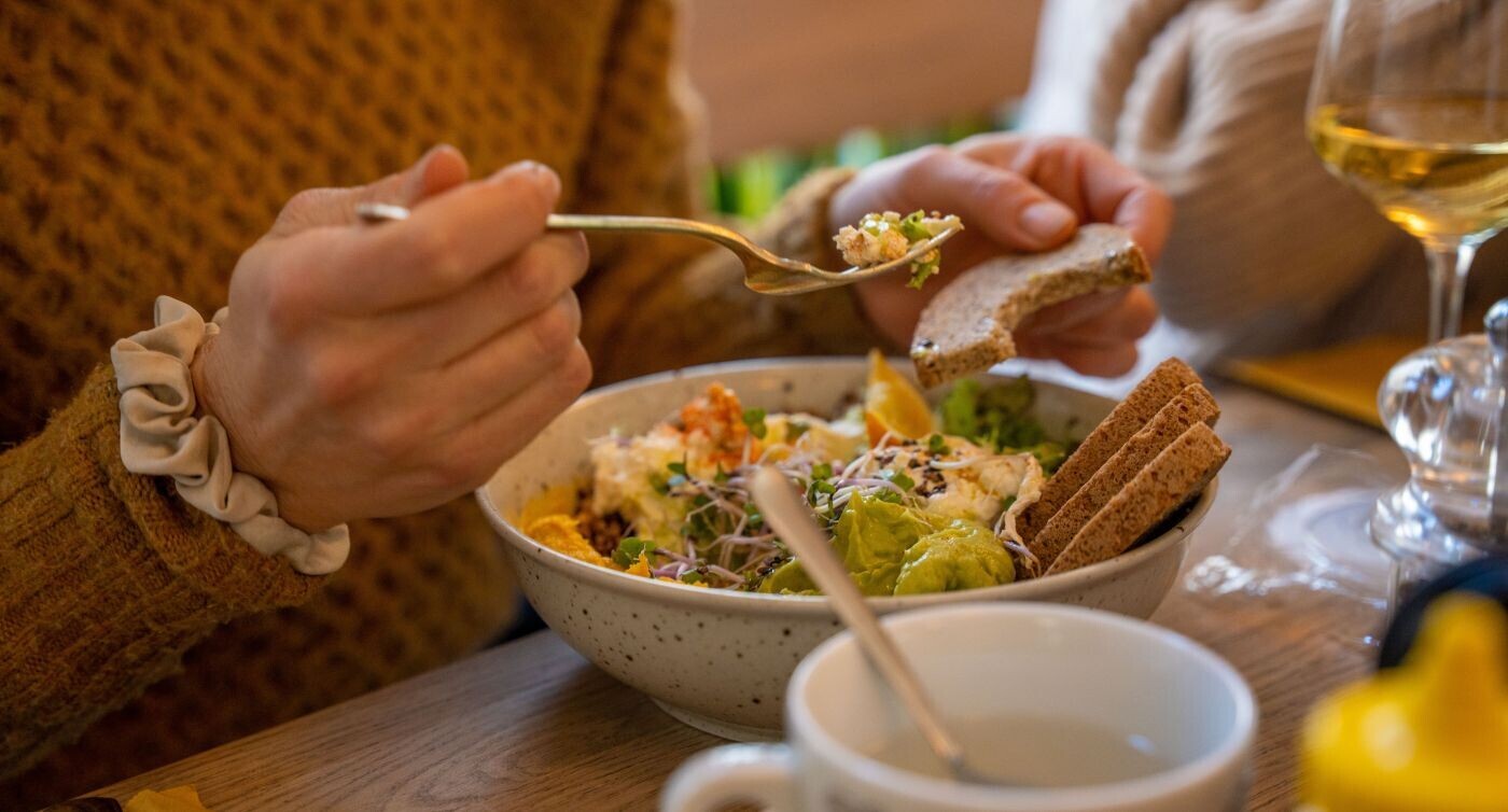 Una donna infilza il suo piatto di insalata con una forchetta.