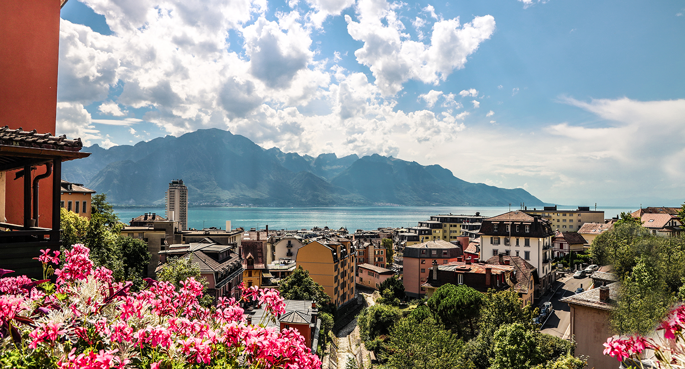 Vista su Montreux dall’alto di un balcone, con il lago Lemano e le montagne sullo sfondo. 