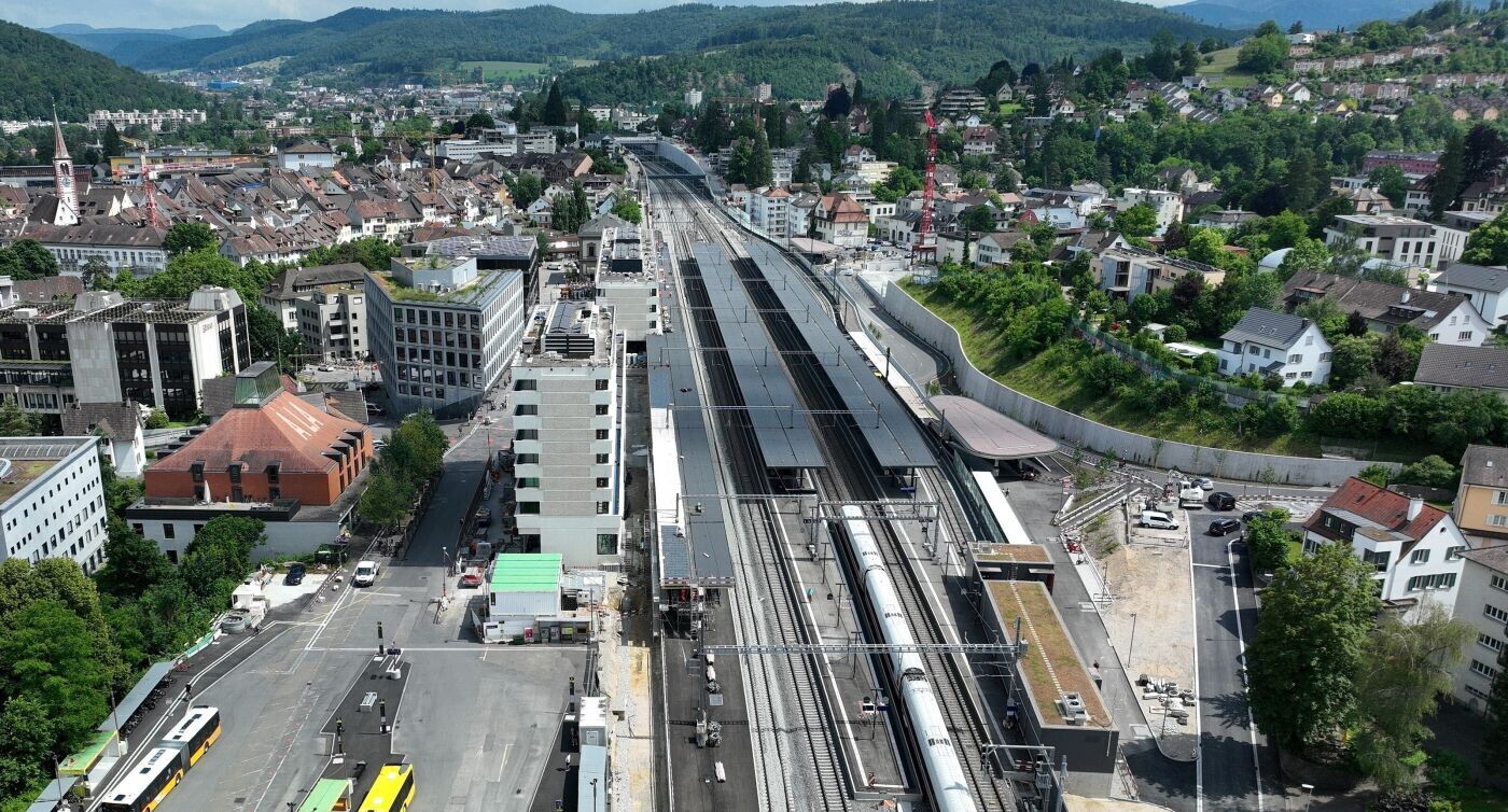 Luftaufnahme der Perrons und Gleise des Bahnhofs Liestal mit Blickrichtung Olten. Links ist das Perron Gleis 1 zu sehen und rechts davon, am gegenüberliegenden Perron das Gleis 2. Der Bahnhof ist von Gebäuden und üppigem Grün umgeben.