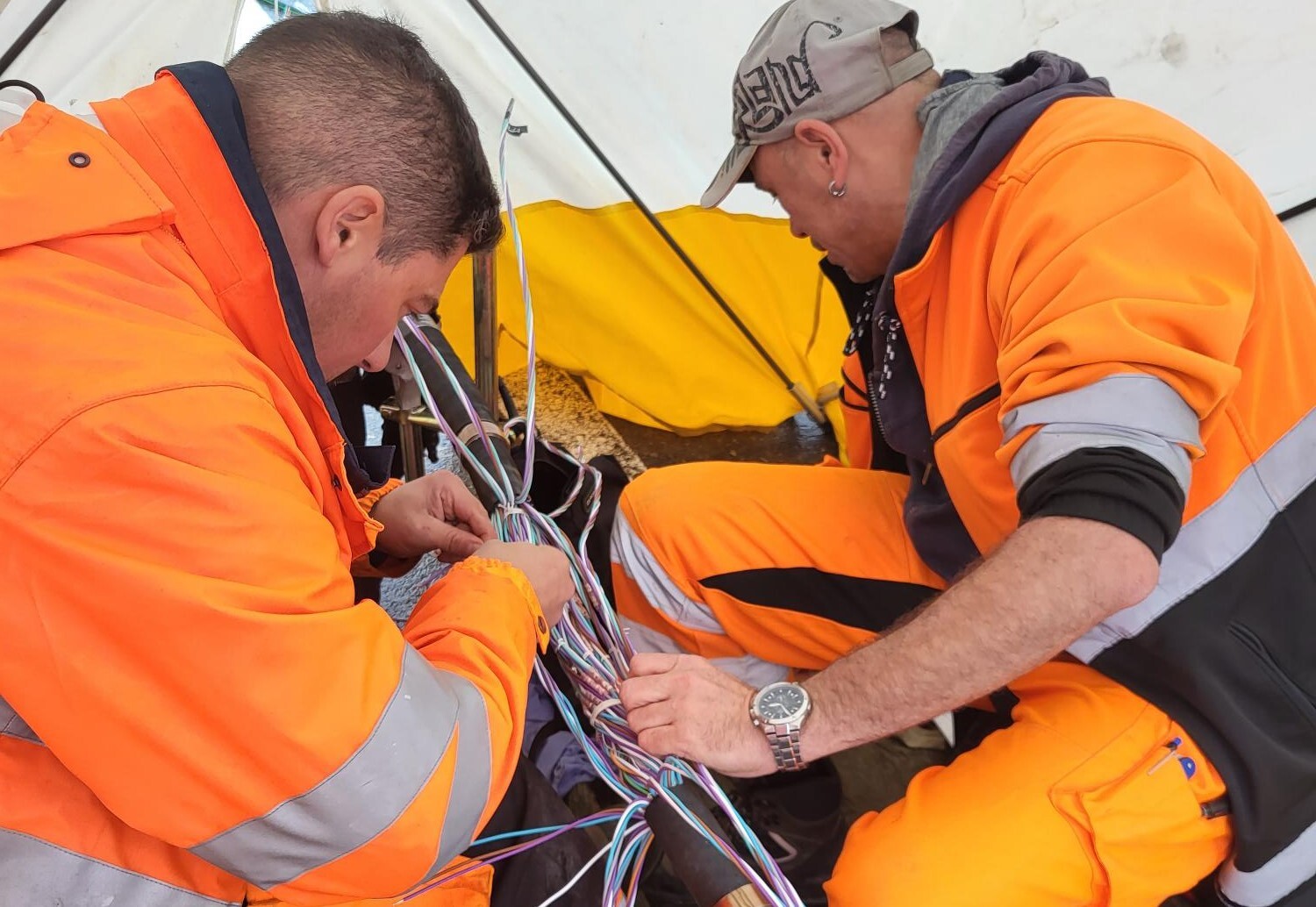 Zwei Mitarbeitende der SBB verbinden beschädigte Kabel